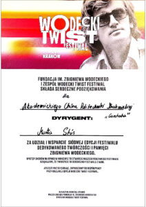 Podziękowanie za występ w trakcie "Wodecki Twist Festiwal". Białe tło, u góry pasek w kolorach białym, żółtym, różowym, czerwonym i śliwkowym. Na jego tle czarno-białe zdjęcie Zbigniewa Wodeckiego oraz białe napisy o treści: "WODECKI TWIST FESTIWAL 7-9.06. KRAKÓW". Poniżej na białym tle są następujące napisy: "FUNDACJA IM. ZBIGNIEWA WODECKIEGO I ZESPÓŁ WODECKI TWIST FESTIWAL SKŁADA SERDECZNE PODZIĘKOWANIA dla Akademickiego Chóru Politechniki Krakowskiej "Cantata" DYRYGENT: Marta Stós ZA UDZIAŁ I WSPARCIE SIÓDMEJ EDYCJI FESTIWALU DEDYKOWANEGO TWÓRCZOŚCI I PAMIĘCI ZBIGNIEWA WODECKIEGO. WYSTĘP CHÓRÓW NA RYNKU W KRAKOWIE TO OTWARCIE NASZEGO RODZINNEGO FESTIWALU. DZIĘKUJEMY, ŻE TWORZYCIE TO SERDUSZKO FESTIWALU Z NAMI. JESZCZE RAZ DZIĘKUJĄC, ZAPRASZAMY DO WSPÓŁPRACY PRZY KOLEJNEJ EDYCJI WODECKI TWIST FESTIWAL. KATARZYNA WODECKA-STUBBS PREZES ZARZĄDU FUNDACJI IM. ZBIGNIEWA WODECKIEGO DYREKTOR WODECKI TWIST FESTIWAL".