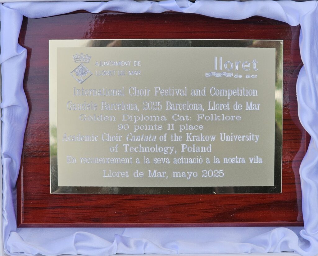 Zdjęcie nagrody zdobytej na festiwalu. Drewniana tabliczka z przyklejona złotą płytką, a na niej u góry po lewej stronie herb miasta z napisem: "AJUNTAMENT DE LLORET DE MAR", po prawej na górze logo miasta. Poniżej napisy: "International Choir Festival and Competition Gaudete Barcelona, 2025 Barcelona, Lloret de Mar Golden Diploma, Cat: Folklore 90 points II place Academic Choir Cantata of the Krakow University of Technology, Poland En reconeixement a la seva actuacio a la nostra vila Lloret de Mar, mayo 2025".